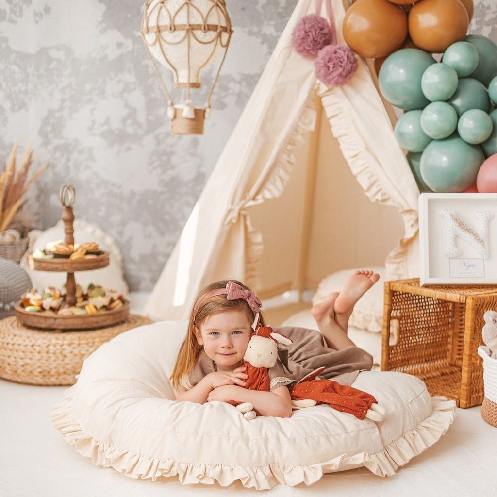 girl lying on MINICAMP Large Floor Cushion With Ruffles in front of kids teepee