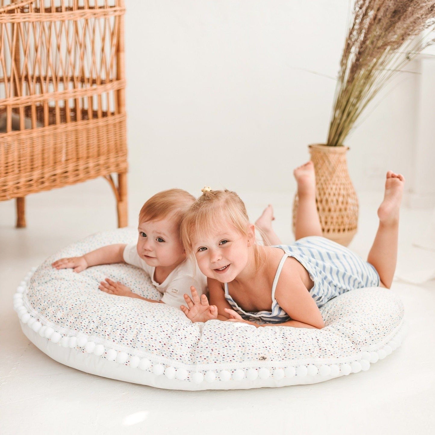two children lying on MINICAMP Big Floor Cushion With Pompoms in Colour Drops on White
