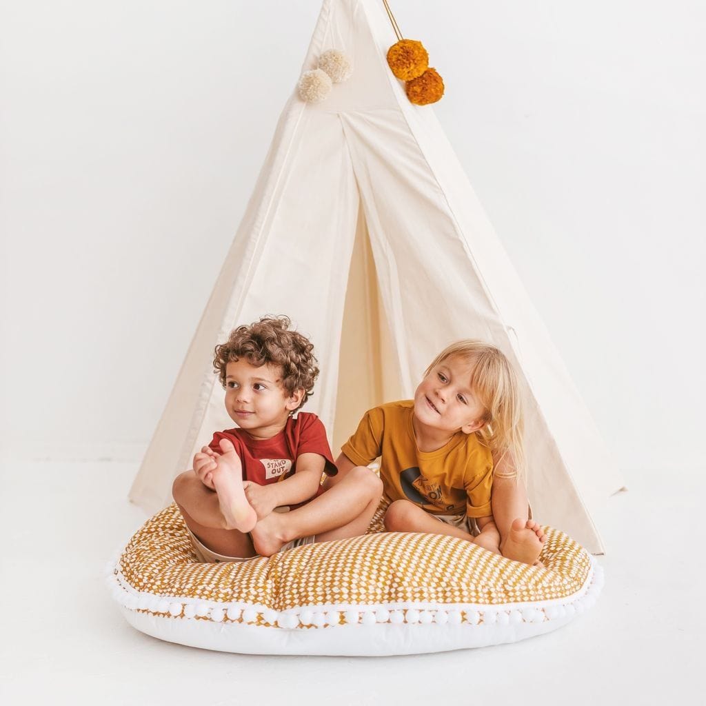 boy and gierl sitting on MINICAMP Big Floor Cushion Rhombus Diamond - Mustard Yellow in front of eco-friendly teepee