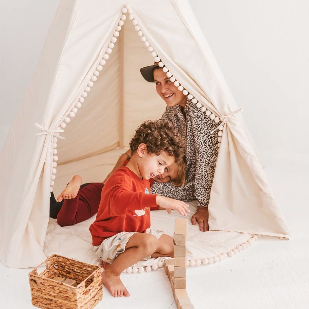 adult and children plahying in MINICAMP Extra Large Kids Teepee Tent With Pom Pom Decor