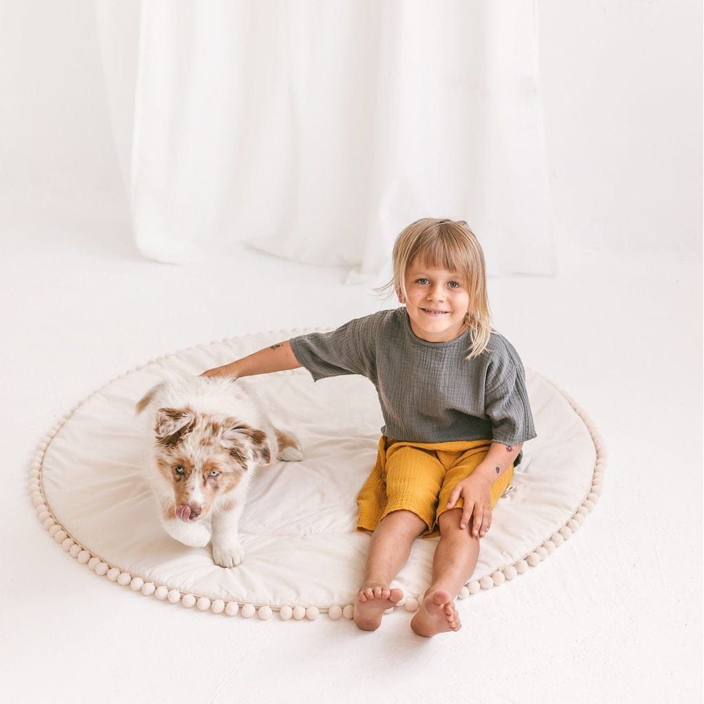 child and dog sitting on MINICAMP Kids Playmat With Pompom Border