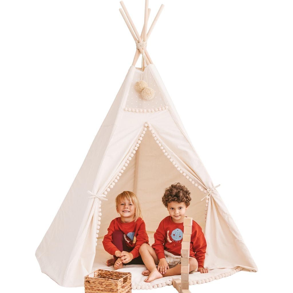 two children sitting in MINICAMP Extra Large Kids Teepee Tent With Pom Pom Decor