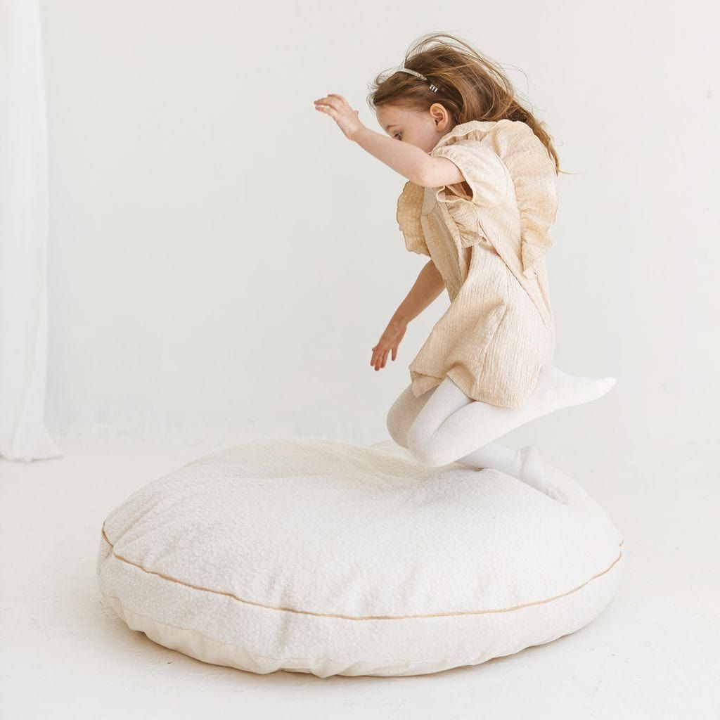 girl jumping onto MINICAMP Boucle Fabric Kids Floor Cushion in Ecru 