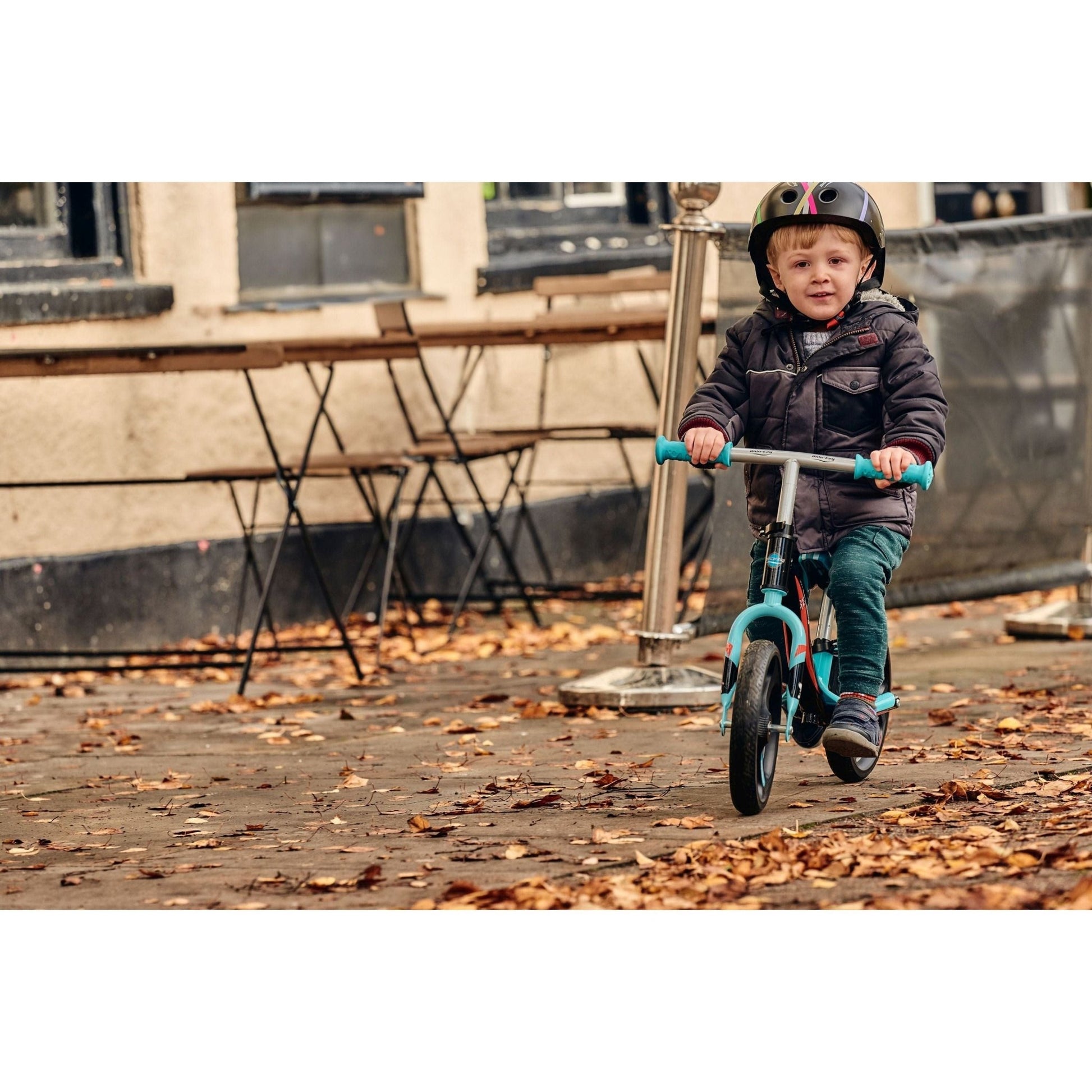 boy riding Ride-Ezy Go Glo Balance Bike - Black & Celeste Green on pavement