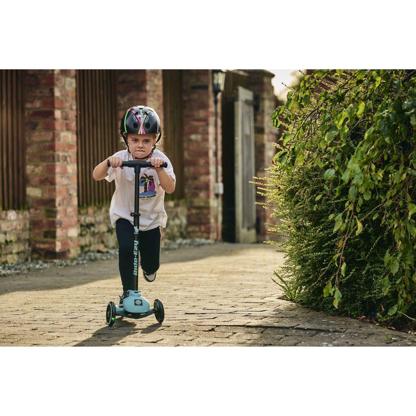 child riding ride-eyz scooter and wearing Ride-Ezy Hector 54-57cms Kids Helmet - Black