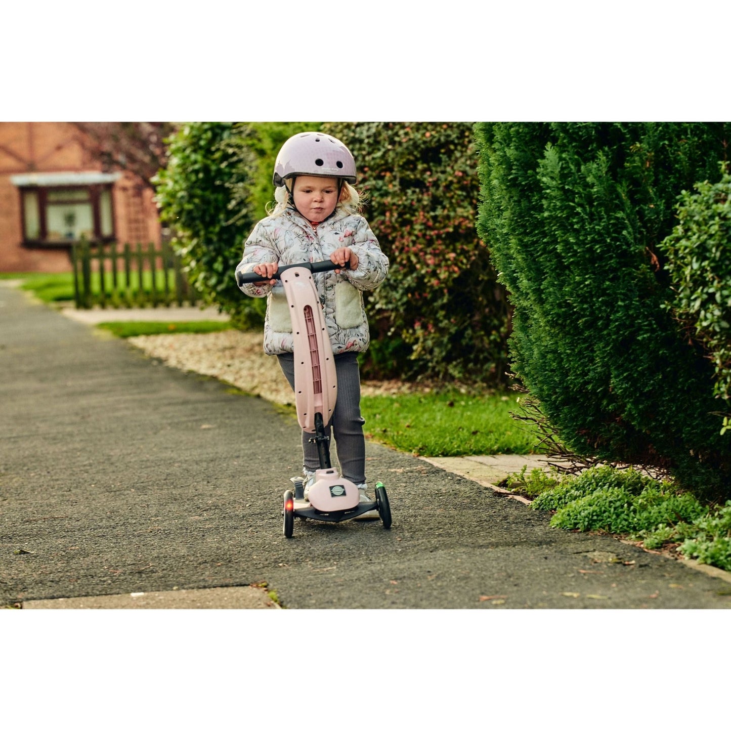 girl riding ride-ezy scooter and wearing Ride-Ezy Hector 48-53cms Kids Helmet - Blossom