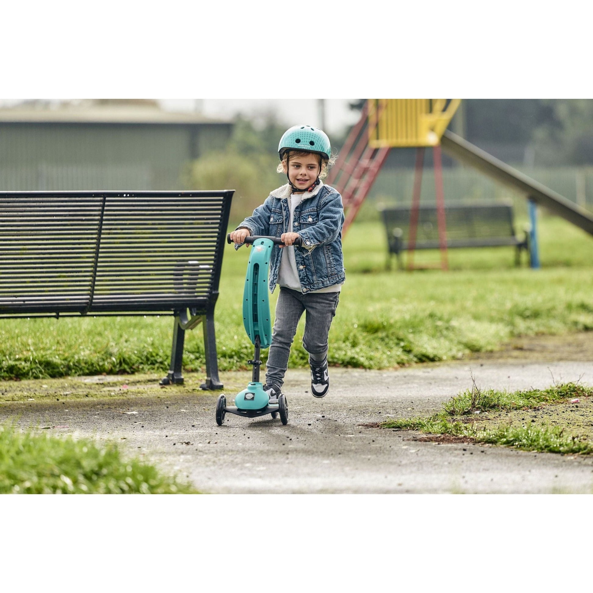 boy in park riding ride-ezy scooter while wearing Ride-Ezy Hector 48-53cms Kids Helmet - Woodland Green