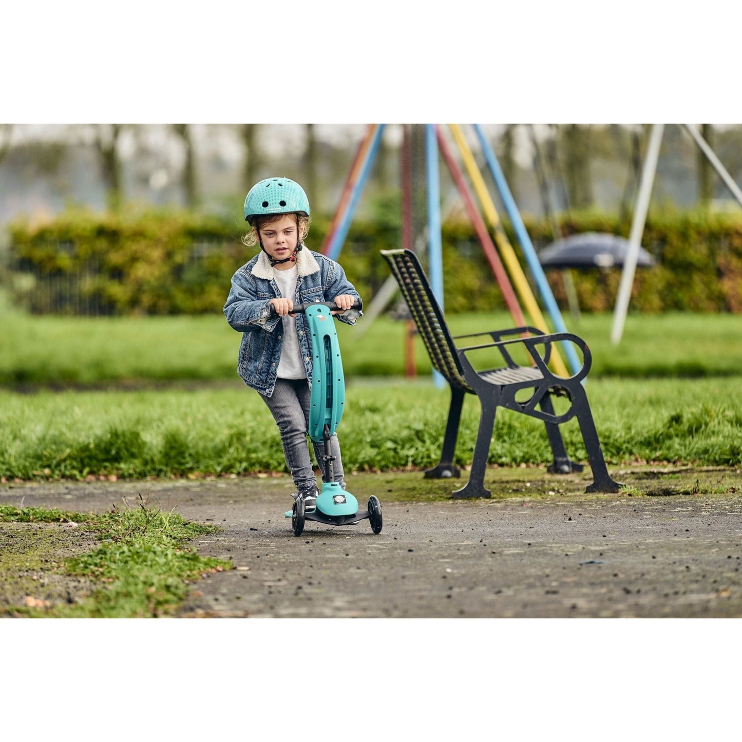 boy riding ride-ezy scooter in front of bench while wearing Ride-Ezy Hector 48-53cms Kids Helmet - Woodland Green
