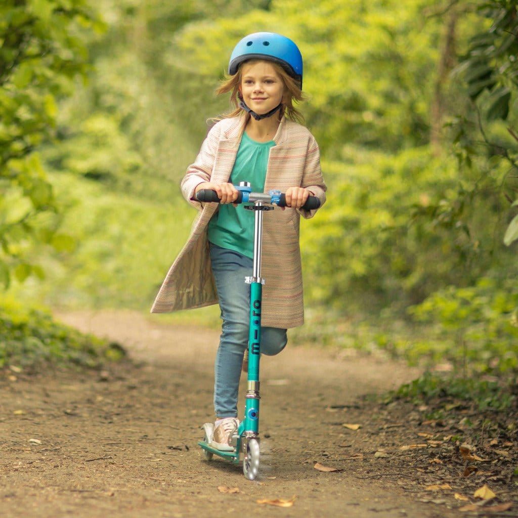 girl riding Micro Scooter Sprite LED - Aqua in woods