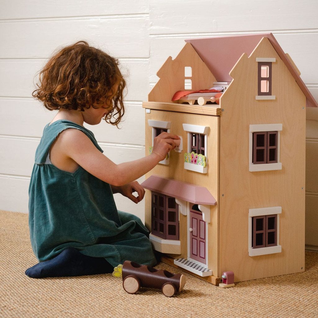 girl kneeling in front of Tender Leaf Wooden Doll House Foxtail Villa + Furniture