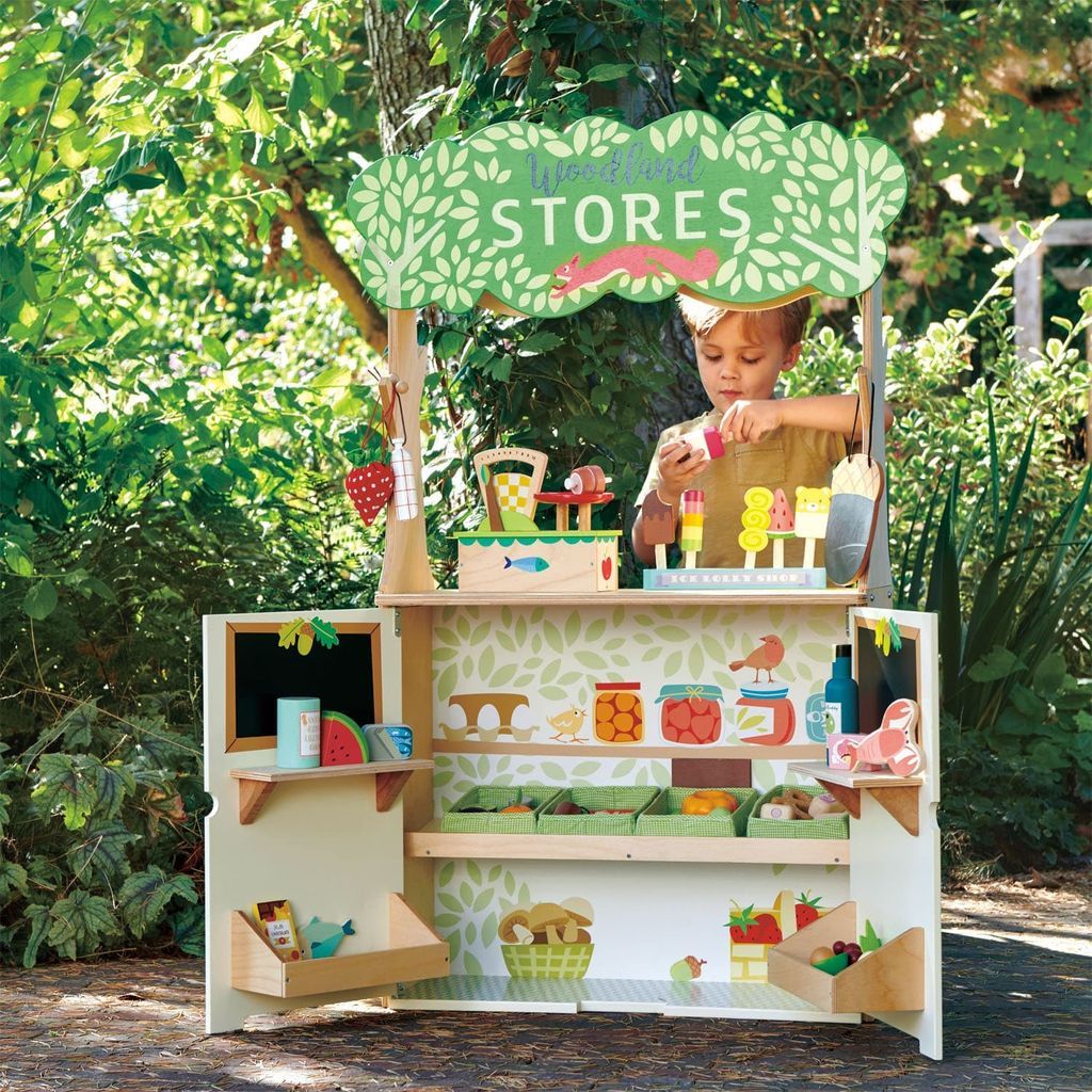 boy playing with Tender Leaf Woodland Stores & Theatre wooden toy  outside