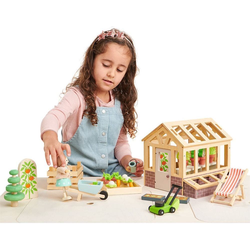 girl playing with Tender Leaf Wooden Greenhouse & Garden Set