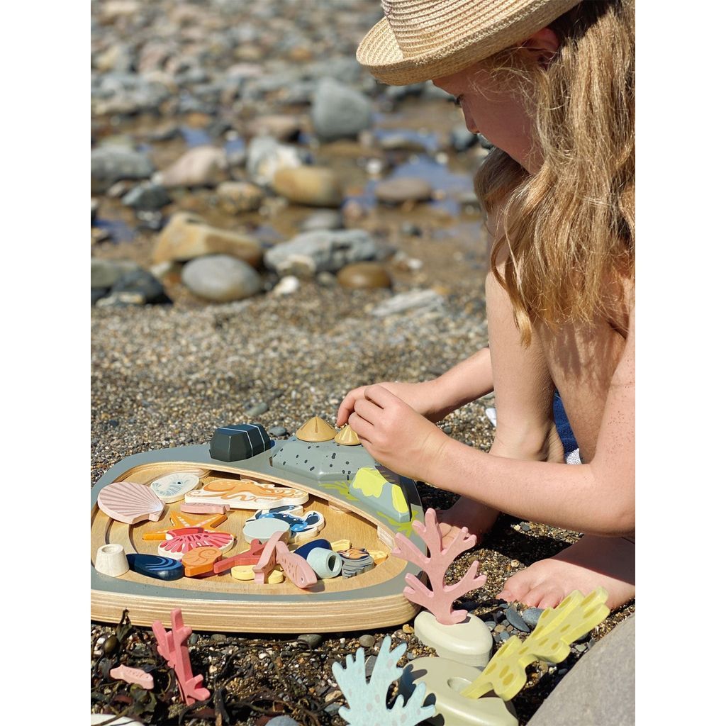 girl on beach playing with Tender Leaf Toys My Little Rock Pool Wooden Toy