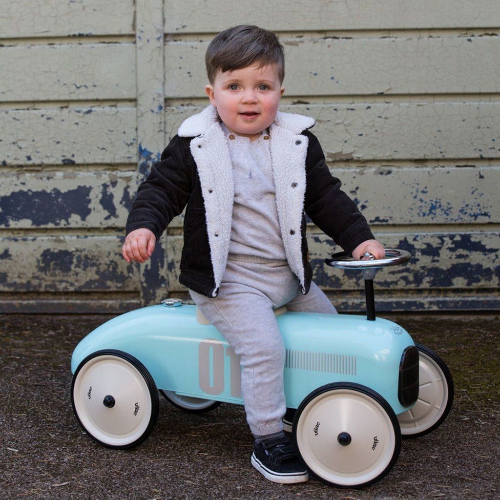 little boy sitting on Vilac Classic Ride-On Racing Car - 18m+ - Light Blue