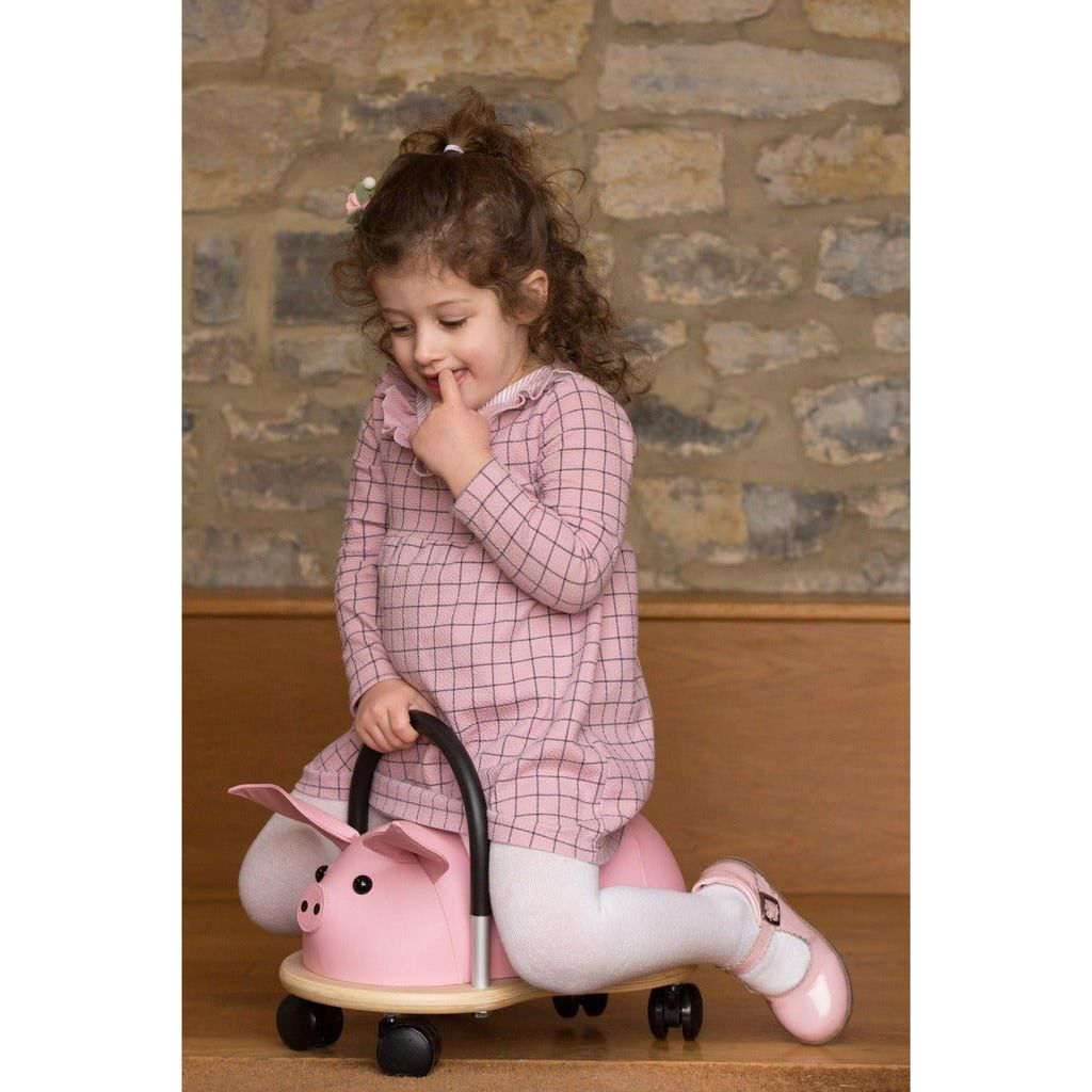 little girl sitting on Wheelybug Ride On - Pig