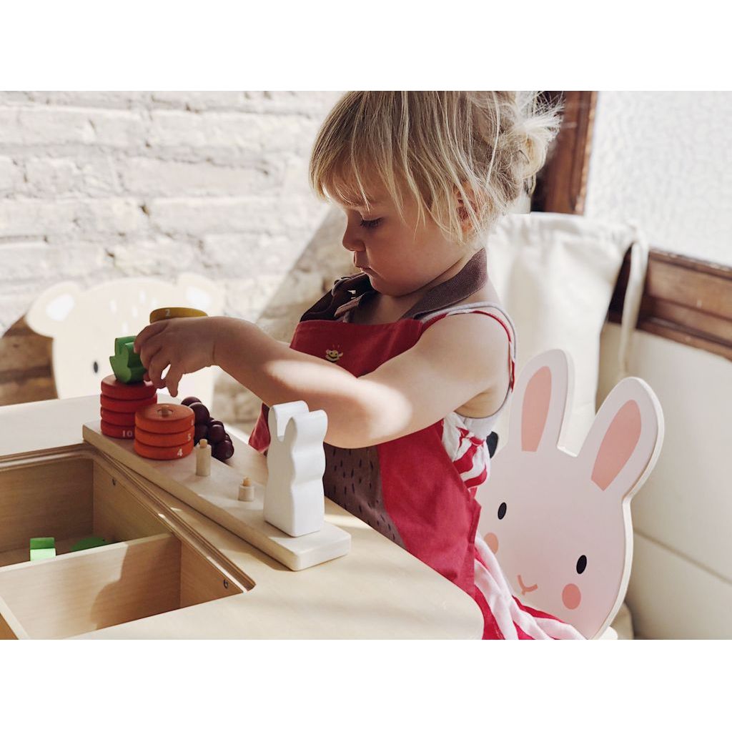 girl sitting at table playing with Tender Leaf Counting Carrots Wooden Counting Game
