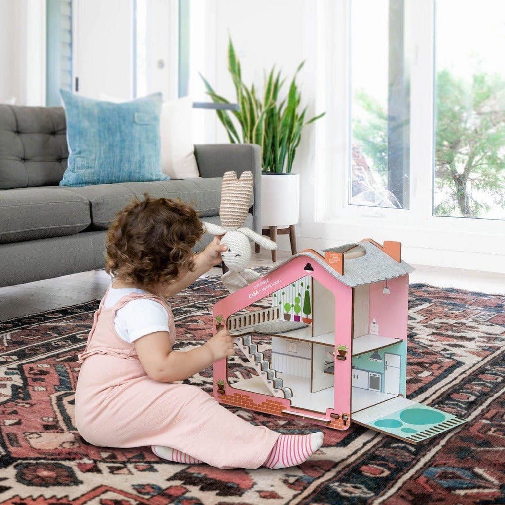 little girl sitting on rug in lounge playing with Mama Toyz Wooden Casa Pink House