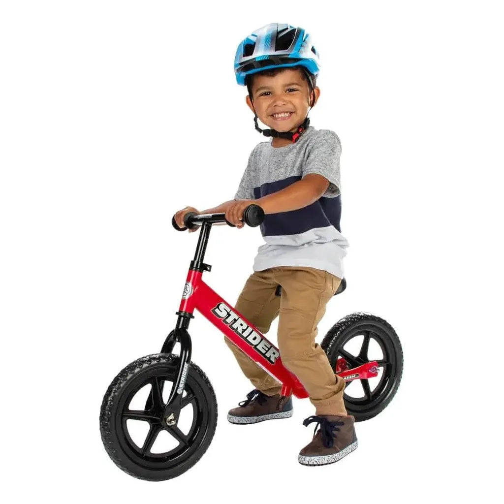 smiling boy riding Strider Classic 12 inch Balance Bike - Red